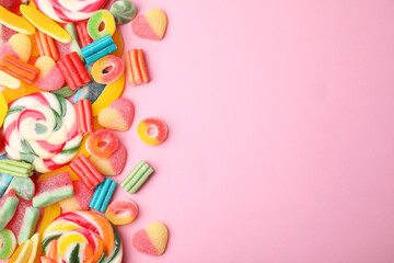 Many different jelly candies and lollipops on pink background, flat lay. Space for text