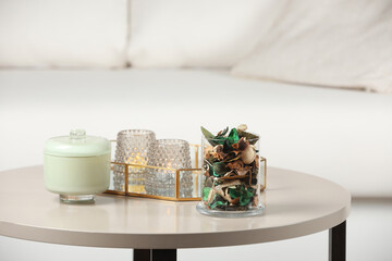 Glass jar with aromatic potpourri of dried flowers and candles on white table indoors