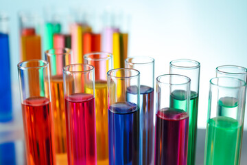 Many test tubes with colorful liquids on turquoise background, closeup