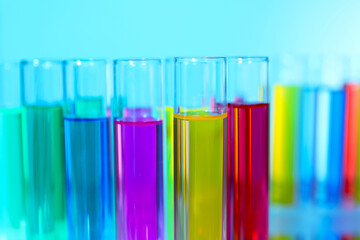 Many test tubes with colorful liquids on blurred background, closeup