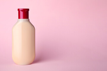 Bottle of shampoo on pale pink background, space for text