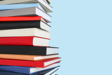 Stack of different books on light blue background, space for text