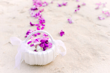 Basket with purple orchids lying on the sand by the sea and has beautiful flower petals at the wedding ceremony being held.