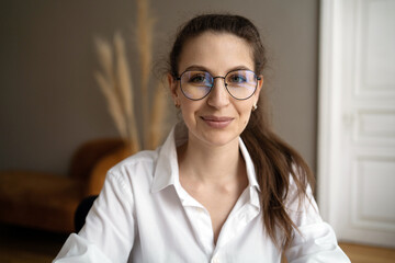 Portrait of a woman with glasses nerd working in a coworking. A manager in a white shirt looks at the camera.