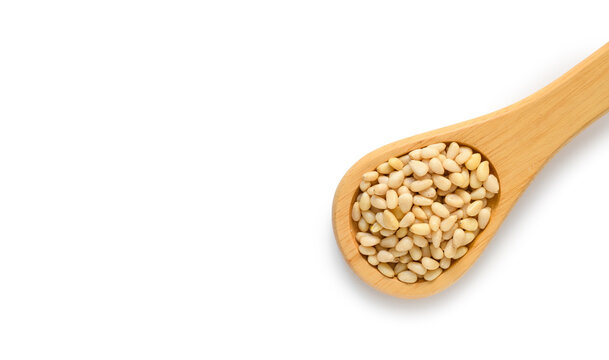 Wooden spoon with pine nuts on a white background. Top view, copy space. Healthy food concept
