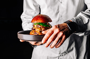 chef holding a burger on a tray