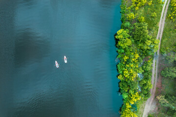two boats on oars float on the river, the coastline and the road on the shore