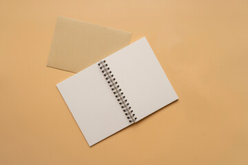 Notebook open spiral bind,  metal ring bind on a orange background with a kraft paper, envelope. Mock up template for notebooks