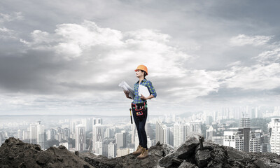 Female engineer in hardhat standing with blueprint