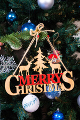 The inscription winter from a tree on a New Year's. On the spruce branches against the background of a snow cover are New Year's blue, white balls with spruce cones and a box with a gift. Christmas