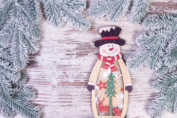 Christmas decorations against blurred background. Small wooden snowman. Rustic wooden snowman snowflake Close up of happy snowman smiling with arms up. Happy holidays greeting card.