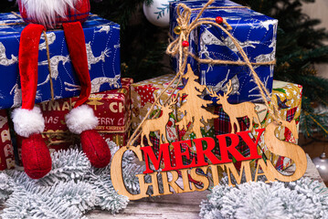 The inscription winter from a tree on a New Year's. On the spruce branches against the background of a snow cover are New Year's blue, white balls with spruce cones and a box with a gift. Christmas