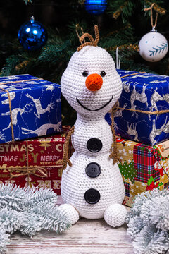 Knitted snowmen in colorful hats and scarves on a blue background. The concept of Christmas, New Year and winter fairy tale.