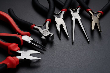 Fototapeta premium Set of different types of pliers and side cutters isolated on black background. Hand tools for repair, construction and maintenance