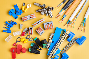 Different electrical tools isolated on yellow background, electrician equipment, wires, terminals, connectors, fuses, switches