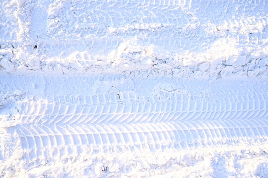 Traces of large tractor wheels in the snow. The imprint of the tread of municipal equipment during snow removal. Snowy, sunny.