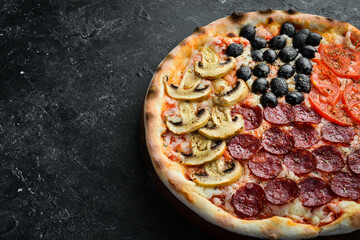 Homemade pizza with sausages, mushrooms, olives and tomatoes. Takeaway food. Home delivery of food. On a black stone background.