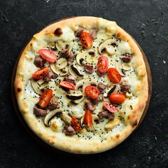 Delicious homemade pizza with veal and mushrooms. Home delivery of food. On a black stone background.