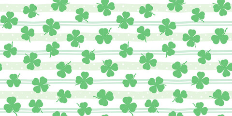 Green shamrocks and clover leaves on a soft striped background. St. Patrick's Day endless texture. Vector seamless pattern for festive wrapping paper, packaging, giftwrap, surface texture and print