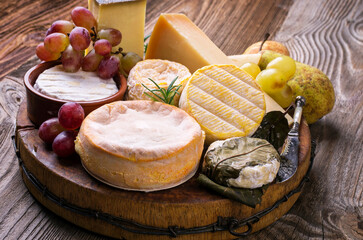 Traditional French cheese platter with soft and hard cheese and fruits served as close-up on a...