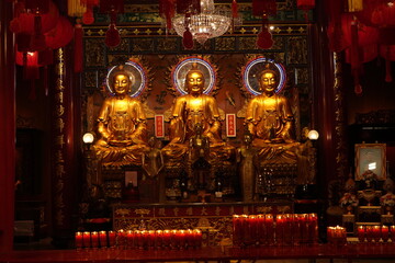 Bangkok : temple bouddhiste dans le quartier chinois avec de nombreux lampions rouges et autels où brulent des bougies  devant des statues de bouddhas dorés 