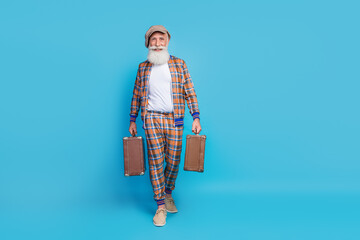 Full length portrait of handsome grandfather hold two bags walking empty space ad isolated on blue color background