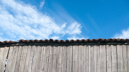 Cobertizo de tablones grises deteriorados y cielo azul