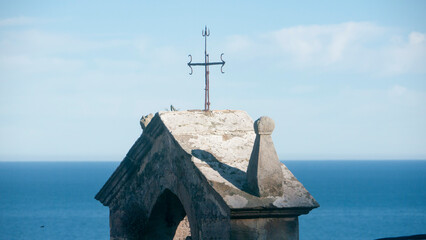 Cruz en pinaculo de iglesia junto al mar
