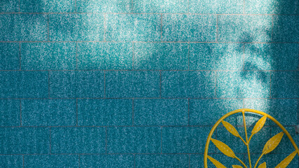 Silla metálica amarilla junto a pared de azulejo azul