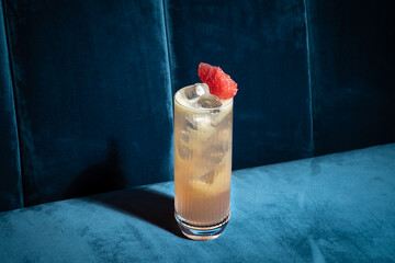 Cocktail on blue background. Modern, stylish drink placed on velvet couch at the bar, night club or...