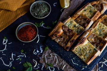 Turkish pide pastry baked in a stone oven served on stone plate with minced meat and cheese