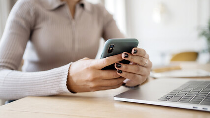 A woman uses a phone in her hands, prints a message, makes an online order, uses an application, keeps records of expenses, dials a PIN code, remembers the password from the mail.