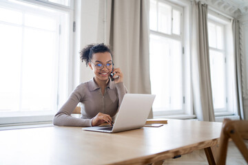 The manager smiles and uses a new laptop and phone for work. A female freelancer writes a message to the client's email and answers a question.