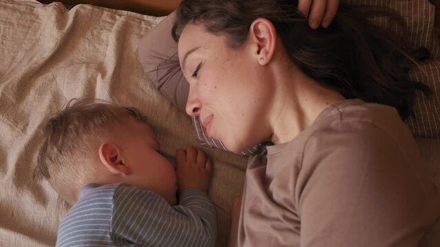 mom next to a sleeping baby. sleeping baby. mom whispers in the ear of a sleeping child. mom kisses sleeping baby