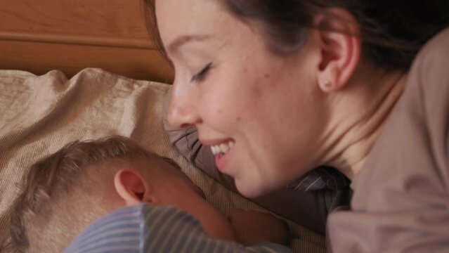 mom next to a sleeping baby. sleeping baby. mom whispers in the ear of a sleeping child. mom kisses sleeping baby