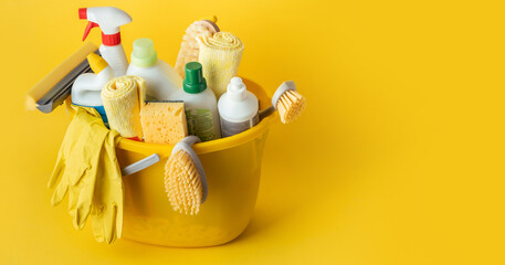 Brushes, bottles with cleaning liquids, sponges, rag and yellow rubber gloves on the yellow...