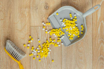 Plastic hand yellow broom with a grey dustpan on the wooden floor. Cleaning the house concept....