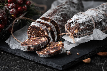 Chocolate salami filled with almonds, hazelnuts and raisins on the black background. Italian sweet...