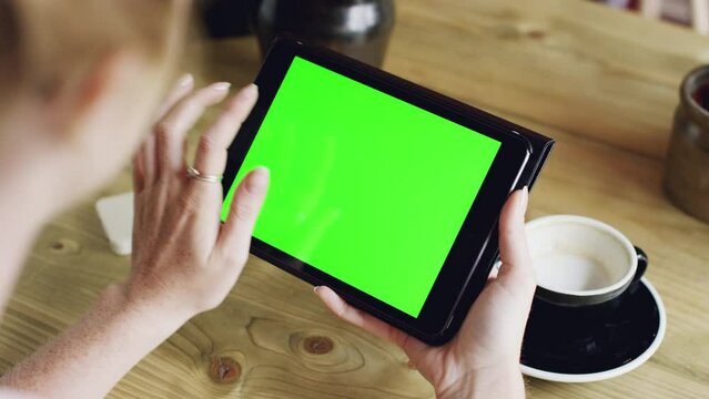 Green screen, tablet and woman in digital marketing at a cafe scrolling or researching social media content. Mockup, product placement and users hands on screen with advertising or marketing space