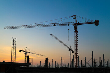 New construction site with crane and structural steel, mechanical equipments on sunset background.