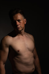 Fototapeta na wymiar Sexy portrait of muscular handsome topless male isolated against a black background