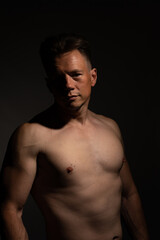 Fototapeta premium Sexy portrait of muscular handsome topless male isolated against a black background