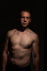 Fototapeta na wymiar Sexy portrait of muscular handsome topless male isolated against a black background