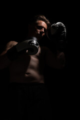 Fototapeta na wymiar Portrait of muscular handsome topless male wearing boxing gloves isolated against a black background