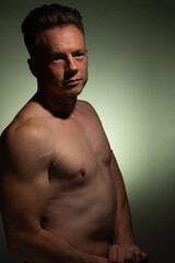 Sexy portrait of muscular handsome topless male isolated against a coloured background