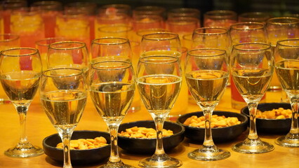 A row of glasses with wine and trays with snacks on a board.