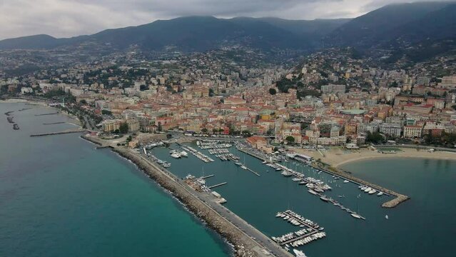 Aerial view of Sanremo, Italian city on the seashore in Liguria, north Italy. Drone flying along the port over beaches and boardwalk with palm trees and Birds Eye of yacht parking in San Remo, Italy.
