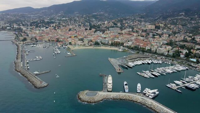 Aerial view of Sanremo, Italian city on the seashore in Liguria, north Italy. Drone flying along the port over beaches and boardwalk with palm trees and Birds Eye of yacht parking in San Remo, Italy.