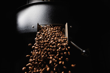 Fresh roasted coffee beans move on professional mixing roaster machines, dark background