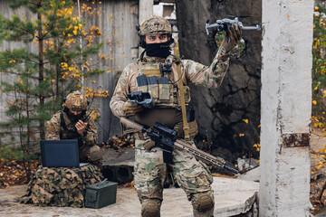 Mobile military base, soldier engineer transmits aerial pictures and data from drone to artillery....
